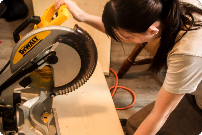 A woman is using a circular saw to cut a piece of wood